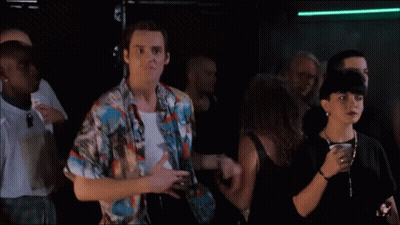 A Man In A Colorful Shirt Is Dancing In A Crowd Of People GIF