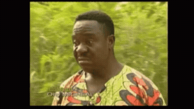 A Man In A Colorful Shirt Is Making A Funny Face While Standing In Front Of A Tree . GIF