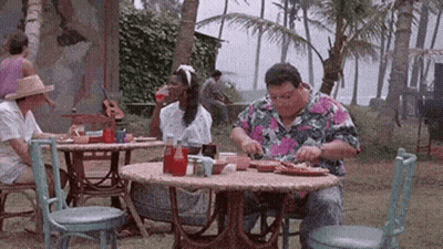 A Man In A Colorful Shirt Is Sitting At A Table Eating GIF
