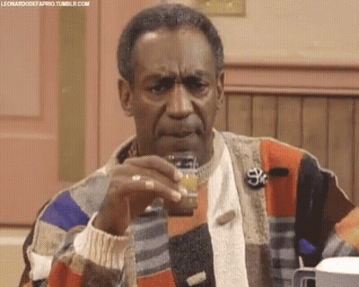 A Man In A Colorful Sweater Is Holding A Small Jar Of Something In His Hand . GIF