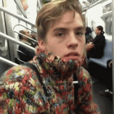 A Man In A Colorful Sweater Is Sitting On A Subway Train . GIF