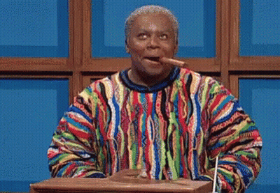 A Man In A Colorful Sweater Is Standing At A Podium And Pointing At Something . GIF