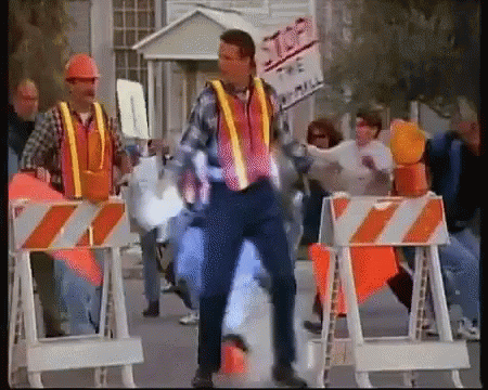 A Man In A Construction Vest Is Dancing In Front Of A Sign That Says Stop GIF