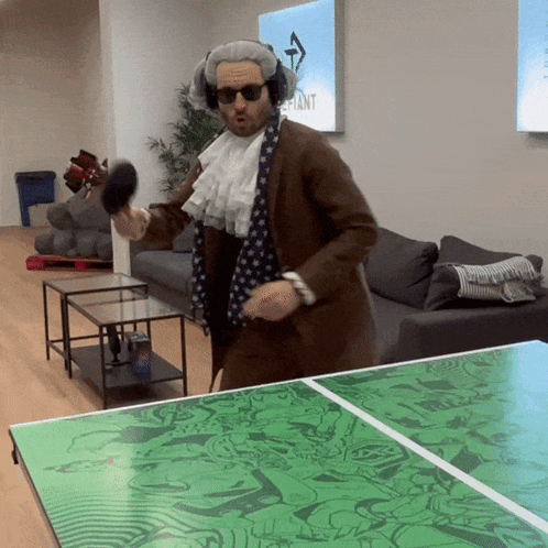 A Man In A Costume Is Playing Ping Pong With A Green Table GIF
