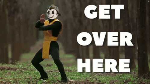 A Man In A Costume Is Standing In The Woods With The Words Get Over Here Behind Him GIF