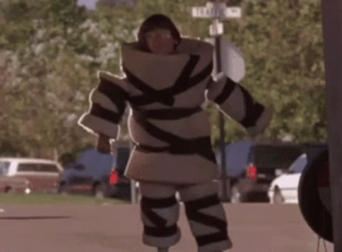 A Man In A Costume Is Walking Down A Street With A Sign That Says Elizabeth St. GIF