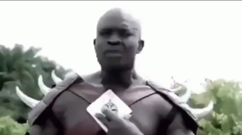 A Man In A Costume With Horns Is Holding A Card . GIF