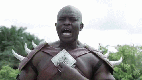 A Man In A Costume With Horns Is Holding A Coin In His Hand . GIF