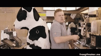 A Man In A Cow Costume Is Standing Next To A Cow Mascot In A Restaurant . GIF