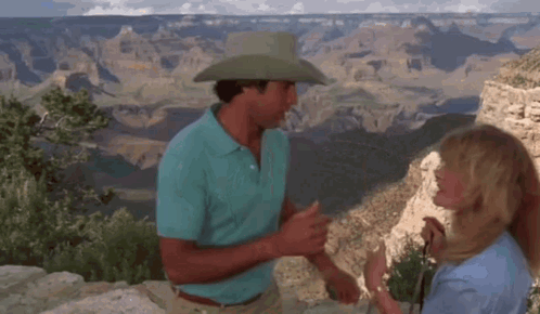 A Man In A Cowboy Hat And A Woman In A Blue Shirt Are Standing Next To Each Other . GIF