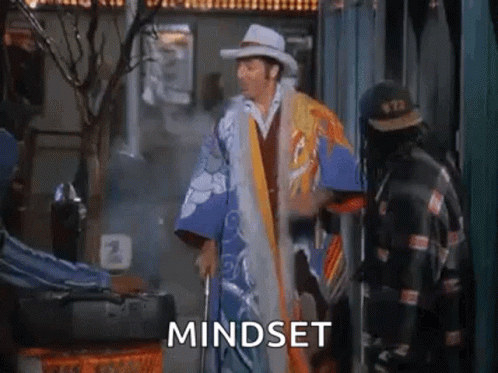 A Man In A Cowboy Hat And Kimono Is Standing Next To A Man With A Cane And The Word Mindset . GIF