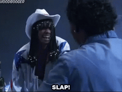A Man In A Cowboy Hat And Sunglasses Is Talking To Another Man In A Blue Shirt . GIF