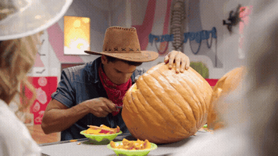 A Man In A Cowboy Hat Carves A Pumpkin GIF