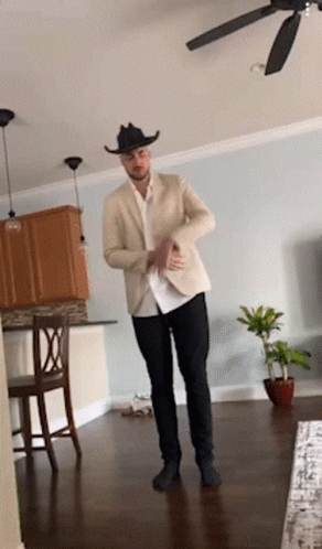 A Man In A Cowboy Hat Is Dancing In A Living Room With A Ceiling Fan GIF