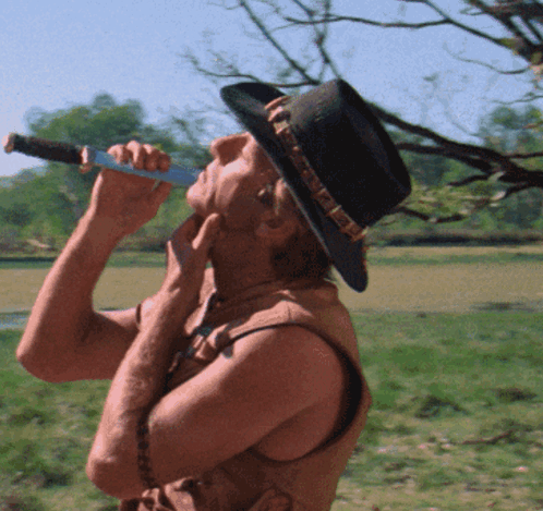 A Man In A Cowboy Hat Is Drinking From A Canteen GIF