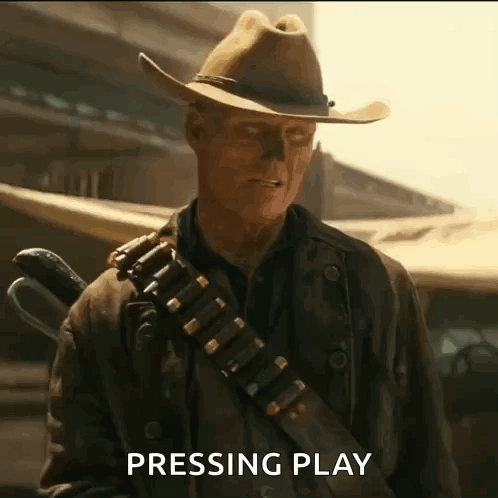 A Man In A Cowboy Hat Is Holding A Gun And Pressing Play GIF