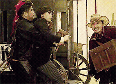 A Man In A Cowboy Hat Is Holding A Trunk And Talking To Two Other Men GIF