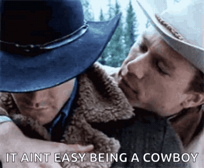A Man In A Cowboy Hat Is Hugging Another Man In A Jacket . GIF