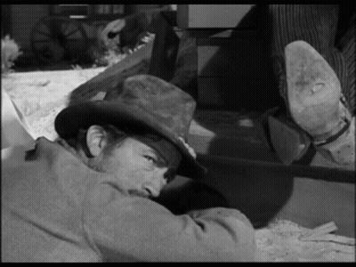 A Man In A Cowboy Hat Is Laying On The Ground . GIF