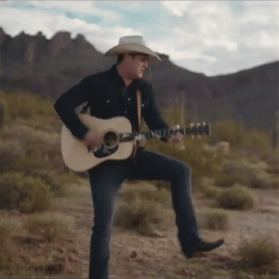 A Man In A Cowboy Hat Is Playing An Acoustic Guitar GIF