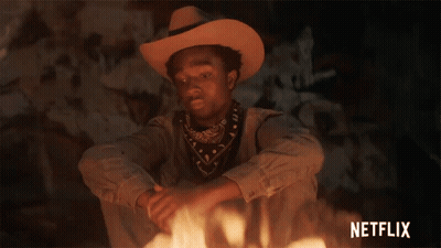 A Man In A Cowboy Hat Is Sitting In Front Of A Fire With Netflix Written In The Corner GIF