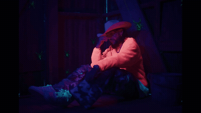A Man In A Cowboy Hat Is Sitting On The Ground GIF