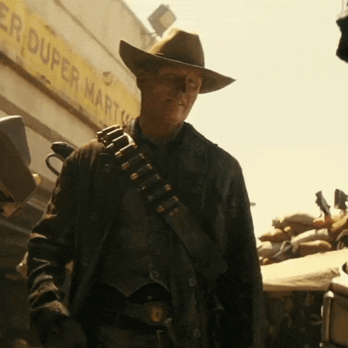 A Man In A Cowboy Hat Is Standing In Front Of A Duper Mart Sign GIF