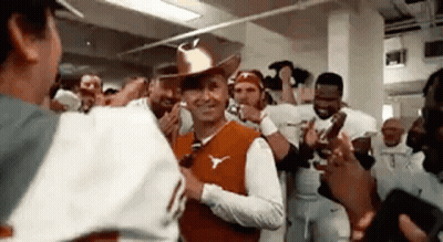 A Man In A Cowboy Hat Is Standing In Front Of A Group Of People . GIF