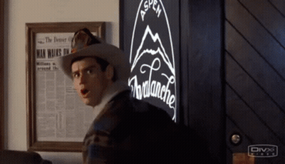 A Man In A Cowboy Hat Is Standing In Front Of A Vending Machine With A Mountain On It . GIF