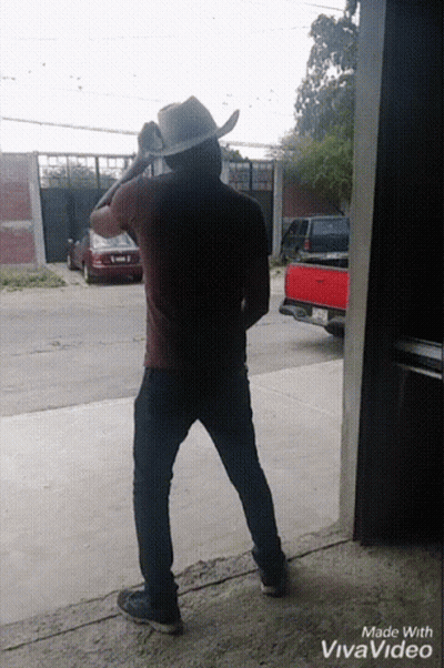 A Man In A Cowboy Hat Is Standing Next To A Red Truck GIF