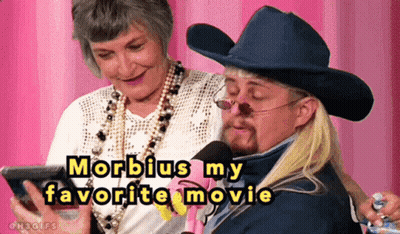 A Man In A Cowboy Hat Is Talking Into A Microphone While A Woman Watches GIF