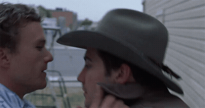 A Man In A Cowboy Hat Kisses Another Man GIF
