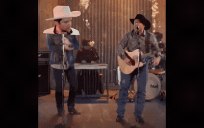 A Man In A Cowboy Hat Sings Into A Microphone GIF