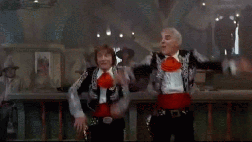 A Man In A Cowboy Hat Sits In A Chair In Front Of A Group Of People Dancing GIF