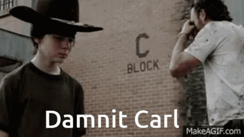 A Man In A Cowboy Hat Stands In Front Of A Brick Wall That Says C Block GIF