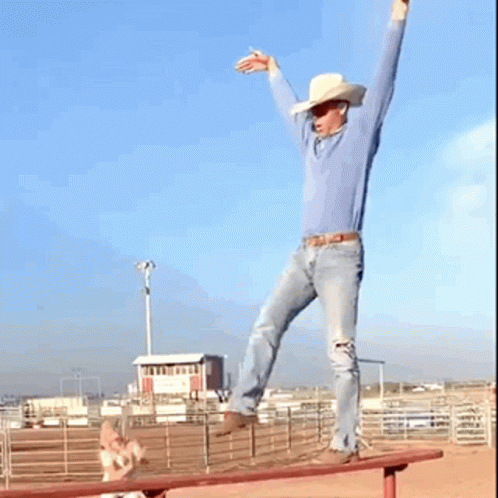 A Man In A Cowboy Hat Stands On A Bench With His Arms Outstretched GIF