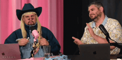 A Man In A Cowboy Hat Talks Into A Microphone While Another Man Looks On GIF
