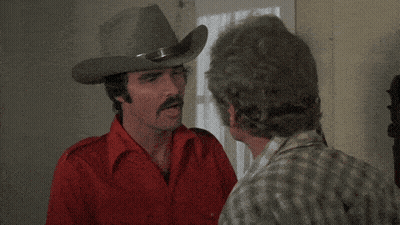 A Man In A Cowboy Hat Talks To Another Man With The Words " For The Good Old American " Above Him GIF