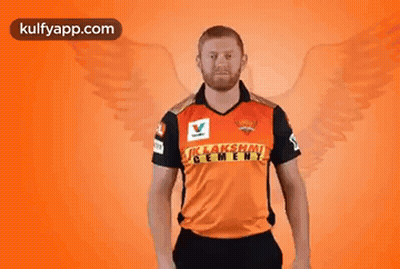 A Man In A Cricket Jersey Is Holding A Bat In His Hand . GIF