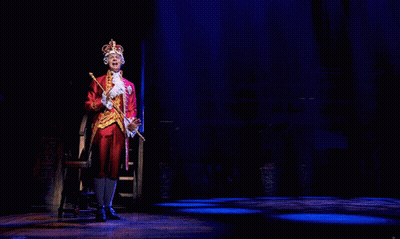 A Man In A Crown Is Holding A Cane GIF