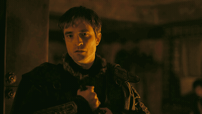 A Man In A Dark Room Holds A Sword In His Hand GIF