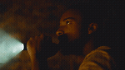 A Man In A Dark Room With A Green Light Shining On Him GIF