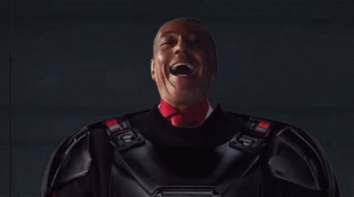A Man In A Dark Room With A Light Coming Out Of The Ceiling GIF