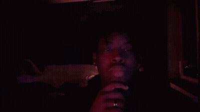 A Man In A Dark Room With A Red Light Shining On His Face GIF