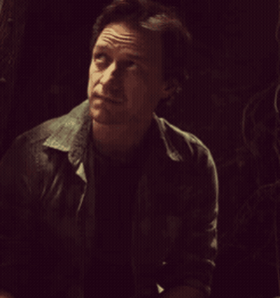 A Man In A Dark Room With His Eyes Closed And A Serious Look On His Face GIF