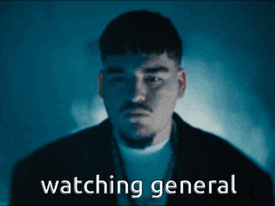 A Man In A Dark Room With The Words " Watching General " Behind Him GIF
