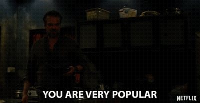 A Man In A Dark Room With The Words " You Are Very Popular " Above Him GIF