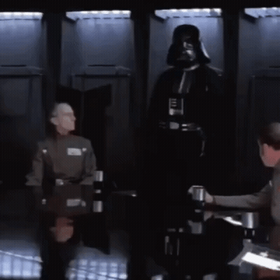A Man In A Darth Vader Costume Is Standing In Front Of A Group Of Men Sitting At A Table GIF