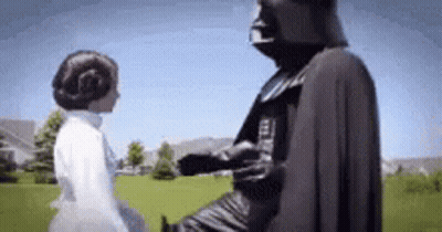 A Man In A Darth Vader Costume Is Standing Next To A Woman In A White Dress In A Field . GIF