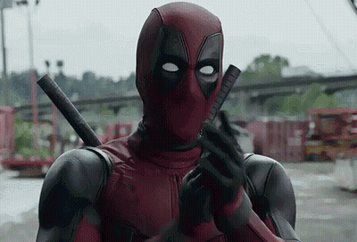 A Man In A Deadpool Costume Is Holding A Gun In His Hand . GIF